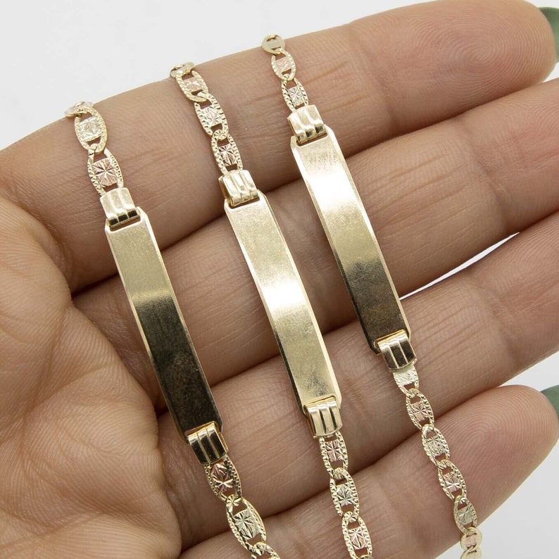 May include: Three gold ID bracelets with a chain link design. The bracelets have a flat, rectangular tag that can be engraved.