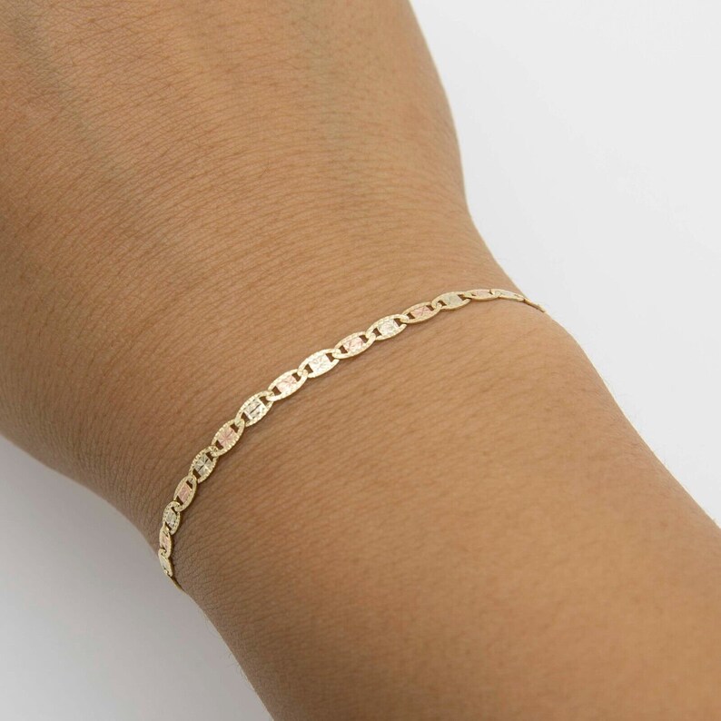 K&ouml;nnte beinhalten: Ein goldenes Armband mit einem Ankerkettenmuster. Das Armband besteht aus drei verschiedenen Goldt&ouml;nen.