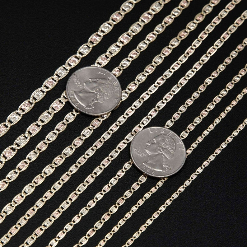 May include: A set of nine gold chains with a mariner link pattern. The chains are arranged in a row, with the largest chain at the top and the smallest chain at the bottom. Each chain is next to a US quarter to show the size difference.