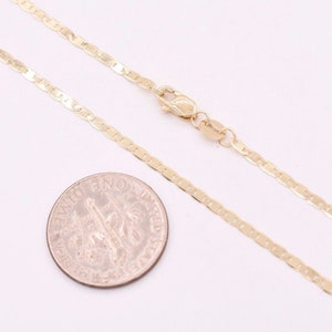 May include: A gold chain necklace with a mariner link design. The chain is shown next to a US dime for size comparison.