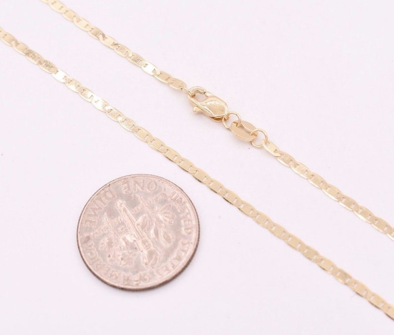May include: A gold chain necklace with a mariner link design. The chain is shown next to a US dime for size comparison.