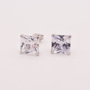 May include: A pair of silver square stud earrings with clear cubic zirconia stones.