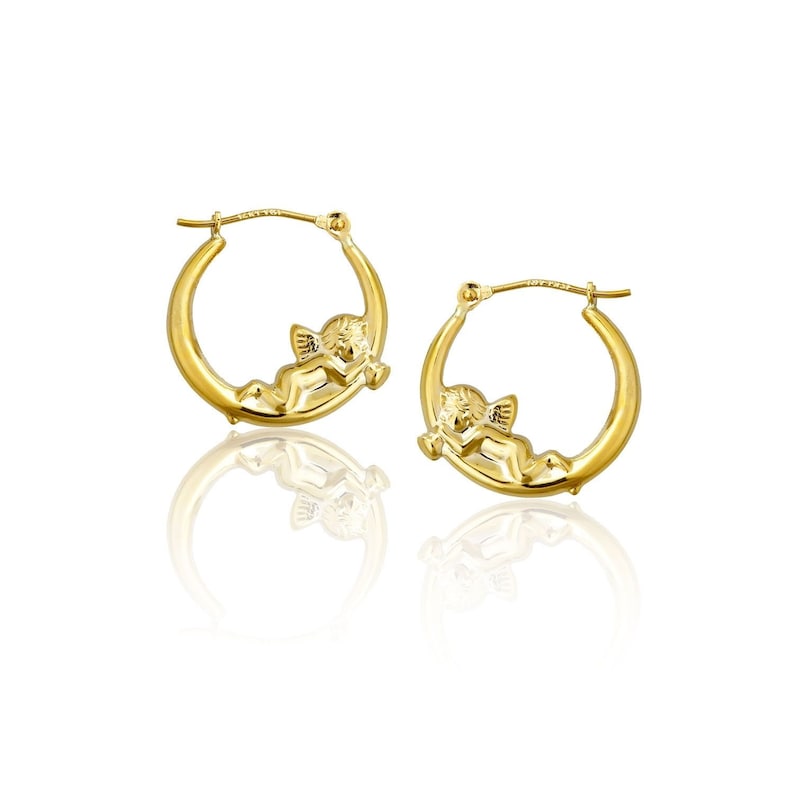 May include: A pair of gold hoop earrings with a cherub design. The cherub is lying on a crescent moon shape.
