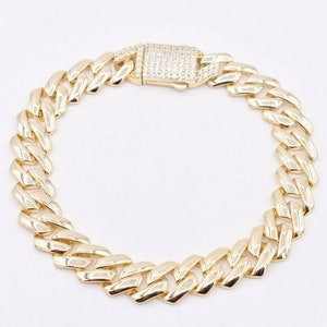 May include: A gold chain bracelet with a diamond-encrusted clasp. The chain is a thick, curb style.