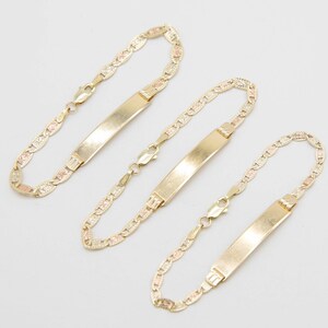 May include: Three gold bracelets with a delicate, patterned chain and a rectangular nameplate charm. The nameplates are blank and ready to be engraved.