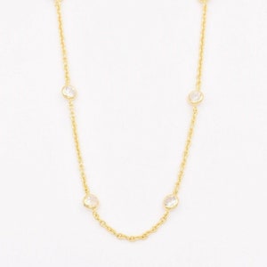 May include: A gold chain necklace with four clear round stones.