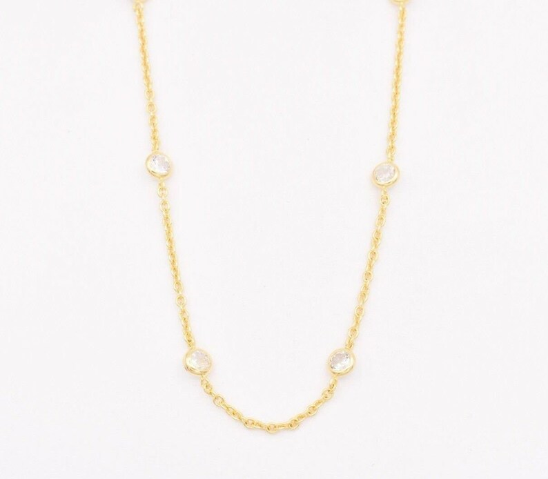 May include: A gold chain necklace with four clear round stones.