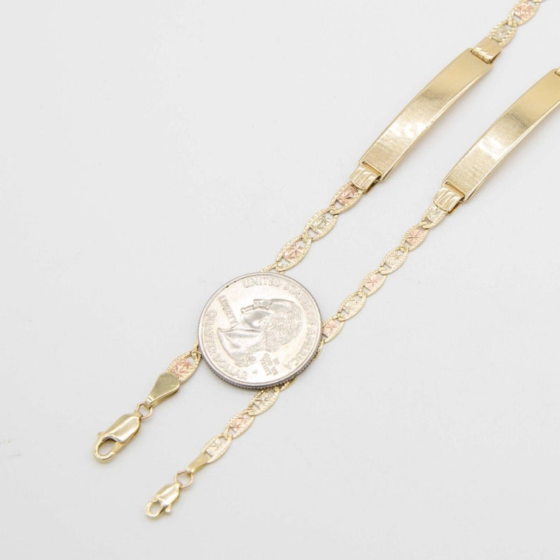 May include: Two gold-toned ID bracelets with a delicate chain design. The chain is a tri-color design with yellow, pink, and white gold. The bracelets are shown next to a US quarter for size reference.