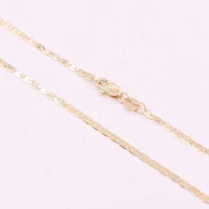 May include: A gold chain necklace with a mariner link style. The chain is laying flat on a white surface.