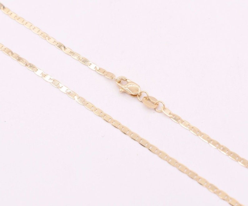May include: A gold chain necklace with a mariner link style. The chain is laying flat on a white surface.