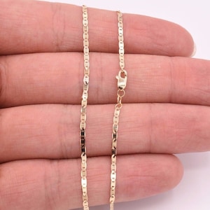 May include: A gold chain necklace with a lobster clasp. The chain is made of small, flat, oval-shaped links.