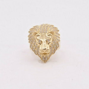 May include: A gold lion head ring with clear cubic zirconia stones.