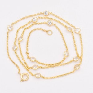May include: A gold chain necklace with clear round stones. The necklace is layered and has a lobster clasp closure.