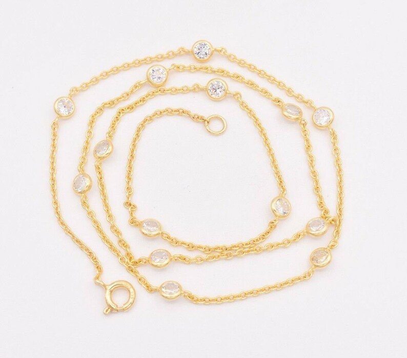 May include: A gold chain necklace with clear round stones. The necklace is layered and has a lobster clasp closure.