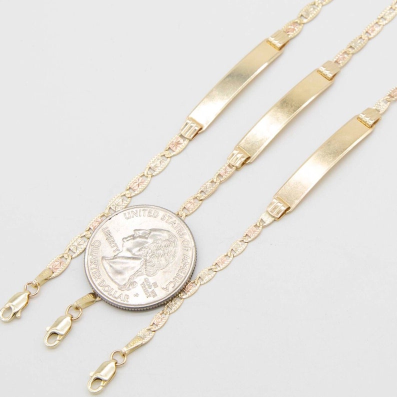 May include: Three gold chain bracelets with a delicate, patterned design. Each bracelet features a flat, rectangular tag.