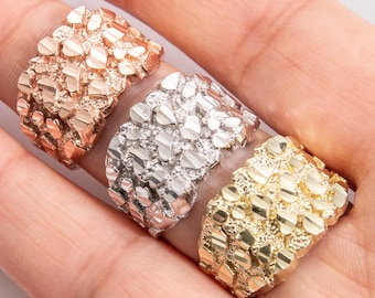 Puede incluir: Tres anillos de oro con un diseño texturizado de corte de diamante. Los anillos son de diferentes tonos de oro: oro rosa, oro blanco y oro amarillo.