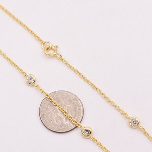 May include: A gold chain necklace with small clear stones. The necklace is shown next to a US quarter for size reference.