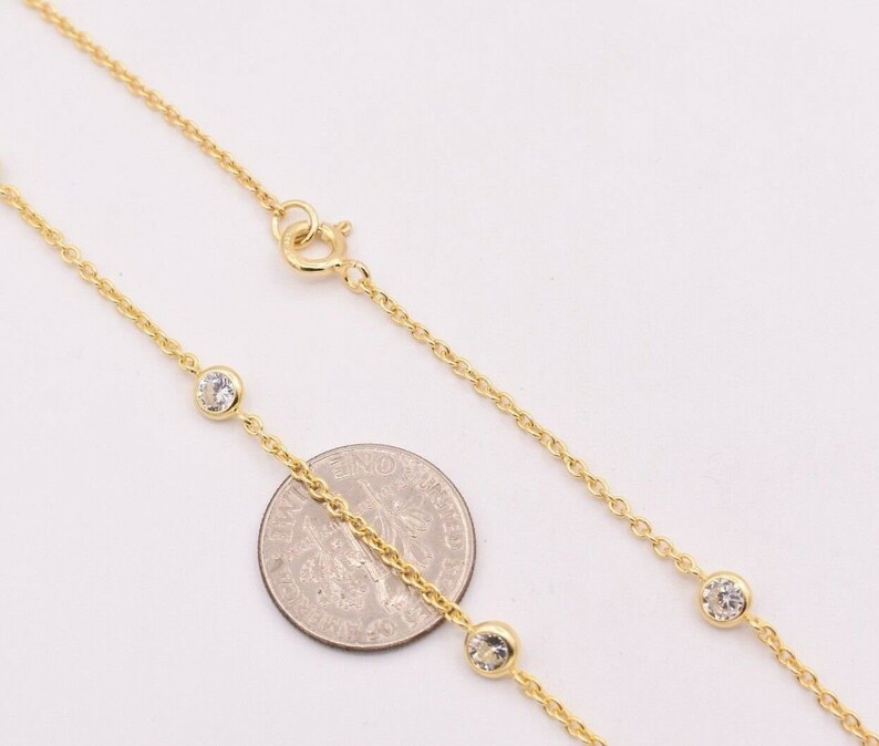 May include: A gold chain necklace with small clear stones. The necklace is shown next to a US quarter for size reference.