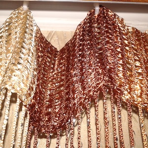 May include: A pair of gold and brown beaded curtains with a woven pattern. The curtains are hanging from a rod and have a fringe at the bottom.