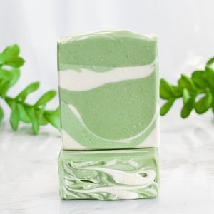 May include: Two bars of handmade soap with a green and white swirl pattern. The soap is made with natural ingredients and is perfect for sensitive skin.