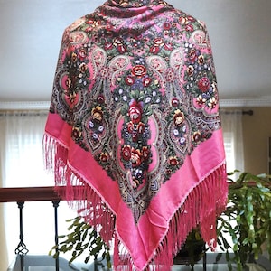 Może przedstawiać: Różowy jedwabny szal z kwiatowym wzorem i frędzlami. Szal jest prezentowany na manekinie.