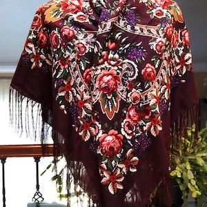 Może przedstawiać: Bordowa chusta z żywym kwiatowym wzorem z czerwonymi, różowymi i białymi różami oraz fioletowymi akcentami. Chusta ma kwadratowy kształt i jest obszyta frędzlami.