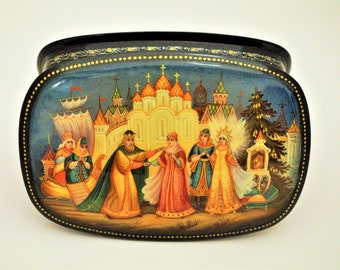 May include: A hand-painted wooden box with a blue background and a scene of a wedding procession. The box is decorated with gold accents and features a couple in traditional Russian clothing.