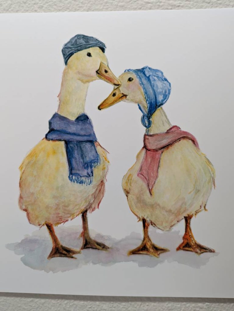 K&ouml;nnte beinhalten: Zwei Aquarell gemalte Enten, die H&uuml;te und Schals tragen. Die Ente links tr&auml;gt einen blauen Schal und einen blauen Hut. Die Ente rechts tr&auml;gt einen rosa Schal und einen blauen Hut. Die Enten schauen sich an und scheinen sich zu k&uuml;ssen.
