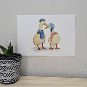 K&ouml;nnte beinhalten: Zwei Aquarell-Enten, die blaue und rosa Schals und H&uuml;te tragen. Die Enten schauen sich an und scheinen sich anzusehen.