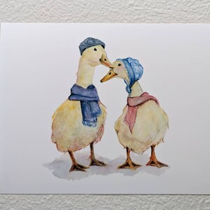 K&ouml;nnte beinhalten: Zwei Aquarell gemalte Enten, die blaue und rosa Schals und H&uuml;te tragen. Die Enten schauen sich an und scheinen sich zu k&uuml;ssen.