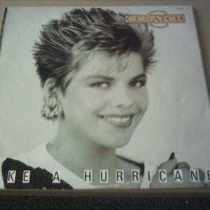 Könnte beinhalten: Ein Schwarzweiß-Albumcover mit einer Frau mit kurzen, stacheligen Haaren. Das Albumcover trägt den Titel "Like a Hurricane" und den Künstlernamen "C.C. Catch" in goldenen Lettern.