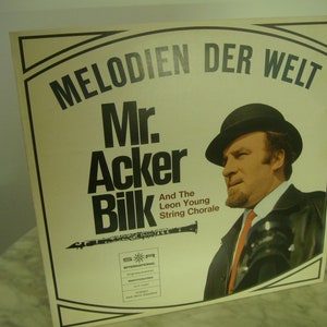 Könnte beinhalten: Ein Vintage-Vinyl-Plattencover mit einem Schwarzweißfoto von Mr. Acker Bilk, einem Klarinettisten, mit dem Text "Melodien Der Welt" und "And The Leon Young String Chorale".