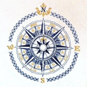 May include: A navy blue compass with gold accents and a white background. The compass features a star design and the cardinal directions are labeled with gold lettering. The compass is surrounded by a decorative border of blue and gold.