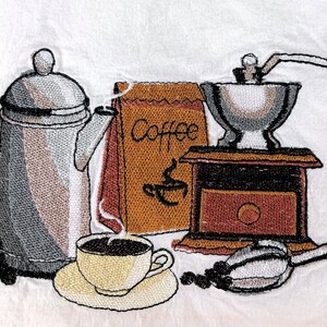 Puede incluir: Una imagen bordada que representa una cafetera, un molinillo de café, una bolsa de granos de café y una taza de café. El molinillo de café está hecho de madera y metal y tiene una manivela. La cafetera es plateada y tiene un pico. La bolsa de granos de café es marrón y tiene la palabra "Coffee" impresa. La taza de café es blanca y tiene un asa marrón. Hay granos de café esparcidos alrededor de la imagen.