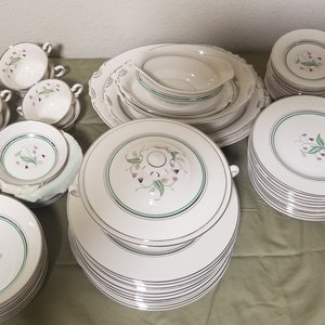 May include: A set of white china dinnerware with a green and pink floral design. The set includes plates, bowls, cups, and saucers.