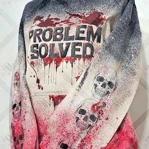 May include: A hooded sweatshirt with a distressed design. The front features the text "PROBLEM SOLVED" in black, with red splatter and drips. The sleeves are adorned with skull graphics and more red splatter, creating a spooky aesthetic.