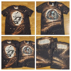 以下が含まれることがあります： ナイトメア・ビフォア・クリスマスのキャラクターが描かれた、漂白剤でデザインされた黒いTシャツ2枚。1枚はジャック・スケリントンとサリー、もう1枚はサリー。シャツの背中には「Simply Meant to Be」の文字が書かれている。