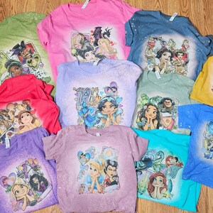 May include: A collection of ten t-shirts featuring various Disney princesses and characters. The shirts are all white with a bleached design and feature characters like Cinderella, Snow White, Ariel, and Jasmine.