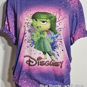 May include: Purple and pink tie-dye t-shirt with a graphic of the character Disgust from the movie Inside Out. The text "Disgust" is printed in green glitter below the character. The shirt is available in adult sizes.