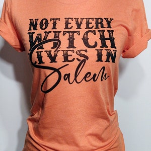 May include: Orange t-shirt with black text that reads "Not Every Witch Lives in Salem".