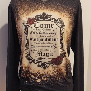 Puede incluir: Camiseta negra de manga larga con un dise&ntilde;o salpicado de lej&iacute;a que presenta una ilustraci&oacute;n de estilo vintage de un cartel enmarcado que dice "Come Little Children I'll take thee away, Into a land of Enchantment Come little children The times come to play, Here in my garden of Magic".