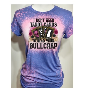 Puede incluir: Una camiseta de color azul y rosa tie-dye con el texto "I don't need tarot cards to read your bullcrap" y un gr&aacute;fico de tres cartas de tarot con una calavera, una luna y un gato.