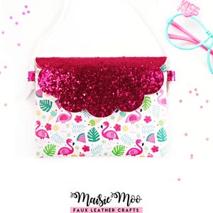 May include: A crossbody bag with a white strap and a scalloped flap covered in dark pink glitter. The body features a repeating pattern of pink flamingos, green palm leaves, watermelon slices, and ice cream cones. A pair of light blue glasses with the word KISS in pink sits nearby.