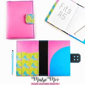 Puede incluir: Una funda para cuaderno A5 de color rosa brillante con una solapa moteada multicolor, un lomo negro y un bolsillo interior azul. La funda tiene costuras azules y un cierre a presión. Se muestra un cuaderno abierto con el texto Fits A5 y un bolígrafo.