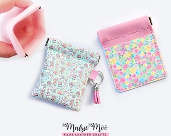 May include: Three small faux leather pouches with snap closures. One pouch is light pink, one features a light blue background with colorful unicorn and cupcake patterns, and one has a floral print. A silver keyring with a pink tassel is attached.