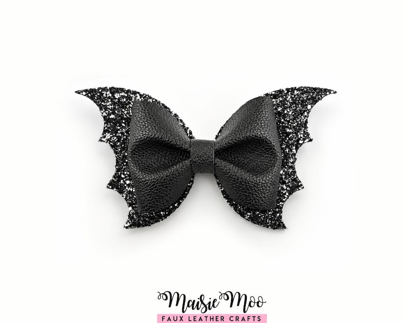 A black, glittery, wing-like bow tie is displayed against a white background.