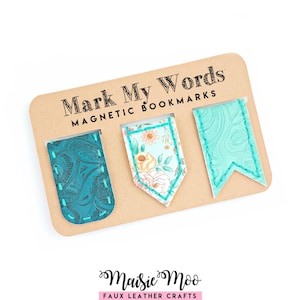 Puede incluir: Tres marcapáginas magnéticos en una tarjeta color canela con la etiqueta Mark My Words. El marcapáginas izquierdo es de color verde azulado oscuro con estampado de cachemira. El central tiene estampado floral. El derecho es verde azulado.