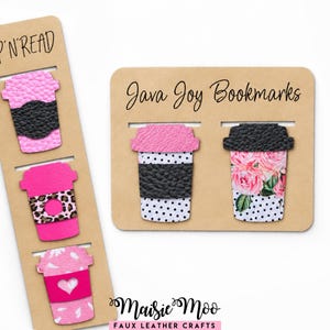Puede incluir: Cinco marcapáginas con forma de taza de café hechos de piel sintética con patrones en rosa, negro y blanco. Los marcapáginas están sujetos a dos tarjetas de cartón beige con las etiquetas SIP'N'READ, Java Joy Bookmarks y Maisie Moo Faux Leather Crafts.