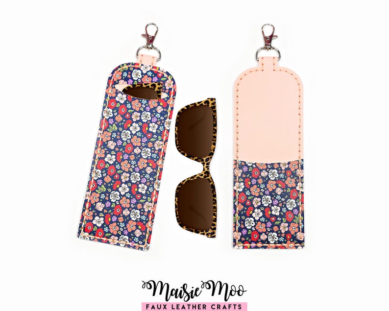 May include: A floral print sunglasses case with a clip, next to a pair of leopard print sunglasses. The case is navy blue with a colorful floral pattern and a pink top. The case is made of faux leather.