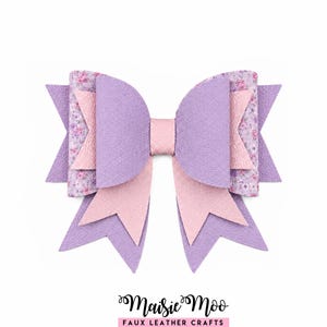 May include: A multi-layered hair bow crafted from faux leather in shades of lavender and light pink, featuring a floral pattern on the back layer and a central knot. The text Maisie Moo Faux Leather Crafts is printed in black below the bow.
